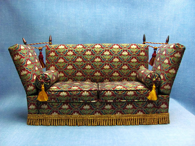 1:12 scale knole sofa replica of the 17th century design, tassled and knobbed.  It was originally used not as comfortable sofa but as a formal throne on which the monarch would have sat to receive visitors.  This replica is created in 1/12 scale by CDHM Artisan Kris Compas of 1 Inch Minis